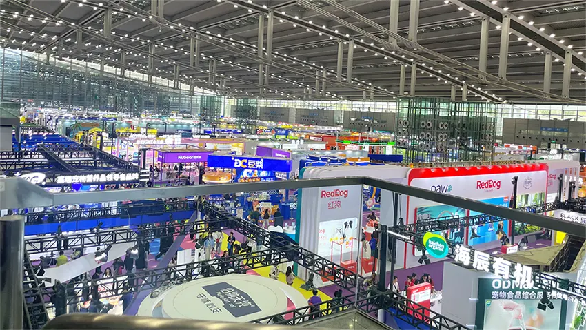 A wide panoramic view of the crowded exhibition hall at the 2026 Shenzhen Pet Fair, showcasing numerous pet tech booths.